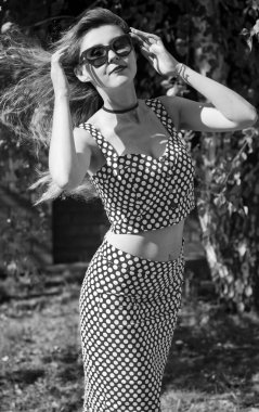 Kırmızı dudaklı ve güneş gözlüklü, pimli takım elbiseli, oyuncu, tatlı ve seksi bir Amerikalı kız. Klasik takım elbiseli bir kadın küçük bir kasabada geziniyor.