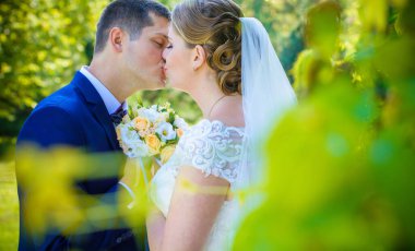 Keyifli öpücüklere sahip güzel bir düğün çifti. İhtiyacın olan tek şey aşk. Artı boyut hassasiyeti gelin ve genç damat.