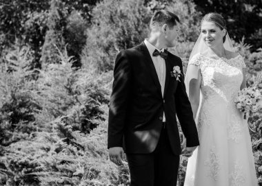 Düğün sonrası mutlu gelin ve damat. Damat gelinden daha genç. Düğün çifti, parkta yeni evliler öpüşüyor.