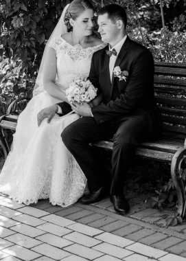 Düğün sonrası mutlu gelin ve damat. Damat gelinden daha genç. Düğün çifti, parkta yeni evliler öpüşüyor.