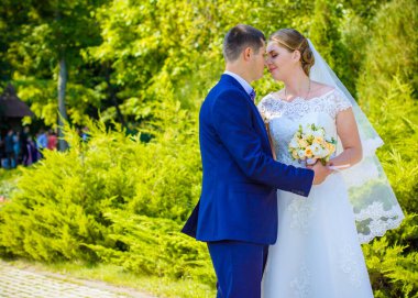 Düğün sonrası mutlu gelin ve damat. Damat gelinden daha genç. Düğün çifti, parkta yeni evliler öpüşüyor.