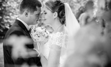 Düğün sonrası mutlu gelin ve damat. Damat gelinden daha genç. Düğün çifti, parkta yeni evliler öpüşüyor.