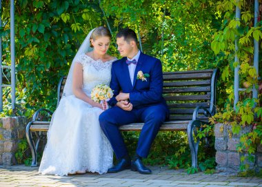 Düğün sonrası mutlu gelin ve damat. Damat gelinden daha genç. Düğün çifti, parkta yeni evliler öpüşüyor.