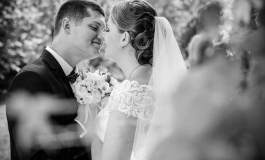 Düğün sonrası mutlu gelin ve damat. Damat gelinden daha genç. Düğün çifti, parkta yeni evliler öpüşüyor.