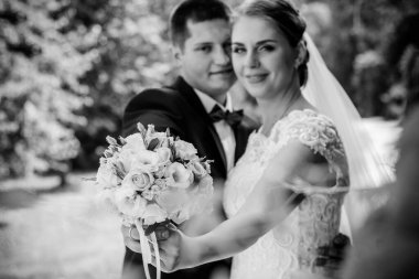 Düğün sonrası mutlu gelin ve damat. Damat gelinden daha genç. Düğün çifti, parkta yeni evliler öpüşüyor.