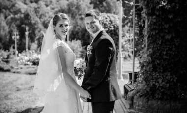 Düğün sonrası mutlu gelin ve damat. Damat gelinden daha genç. Düğün çifti, parkta yeni evliler öpüşüyor.