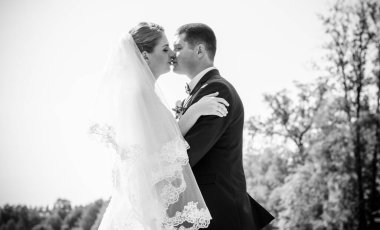 Düğün sonrası mutlu gelin ve damat. Damat gelinden daha genç. Düğün çifti, parkta yeni evliler öpüşüyor.