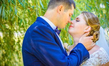 Düğün sonrası mutlu gelin ve damat. Damat gelinden daha genç. Düğün çifti, parkta yeni evliler öpüşüyor.