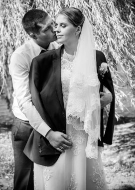 Düğün sonrası mutlu gelin ve damat. Damat gelinden daha genç. Düğün çifti, parkta yeni evliler öpüşüyor.