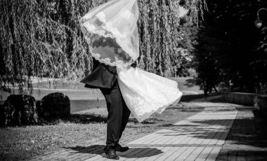 Düğün sonrası mutlu gelin ve damat. Damat gelinden daha genç. Düğün çifti, parkta yeni evliler öpüşüyor.