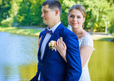 Düğün sonrası mutlu gelin ve damat. Damat gelinden daha genç. Düğün çifti, parkta yeni evliler öpüşüyor.