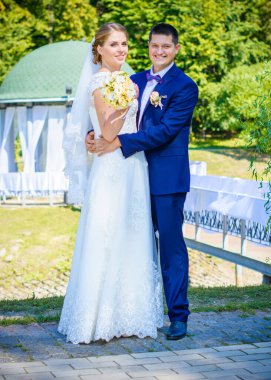 Düğün sonrası mutlu gelin ve damat. Damat gelinden daha genç. Düğün çifti, parkta yeni evliler öpüşüyor.