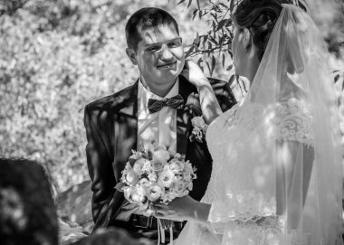 Düğün sonrası mutlu gelin ve damat. Damat gelinden daha genç. Düğün çifti, parkta yeni evliler öpüşüyor.