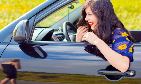 Beautiful curly brunette woman sit in auto on a road and correct make up, dangerous for woman