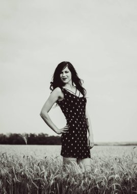 Klasik tarz, altın bir sahada genç bir kadını rahatlatıyor. Yaz güneşinde bir çayırda dinlen. Güzel bir kız portresi, dalgalı saçlar. Güzel esmer bayan buğday tarlasında gün batımında