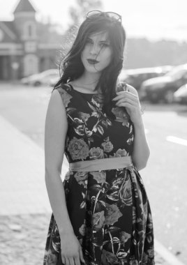 Kıvırcık saçlı, 50 'li yaşlarda, siyah elbiseli, kırmızı güllü muhteşem esmer kadın. Güzel kız sokaklarda yürüyor ve iyi bir ruh hali içinde harika hissediyor.