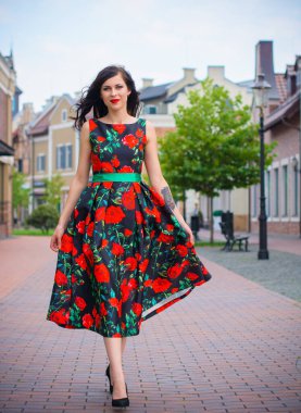 Kıvırcık saçlı, 50 'li yaşlarda, siyah elbiseli, kırmızı güllü muhteşem esmer kadın. Güzel kız sokaklarda yürüyor ve iyi bir ruh hali içinde harika hissediyor.