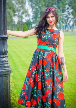 Kıvırcık saçlı, 50 'li yaşlarda, siyah elbiseli, kırmızı güllü muhteşem esmer kadın. Güzel kız sokaklarda yürüyor ve iyi bir ruh hali içinde harika hissediyor.