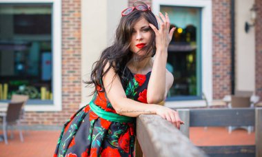 Kıvırcık saçlı, 50 'li yaşlarda, siyah elbiseli, kırmızı güllü muhteşem esmer kadın. Güzel kız sokaklarda yürüyor ve iyi bir ruh hali içinde harika hissediyor.