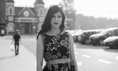 Kıvırcık saçlı, 50 'li yaşlarda, siyah elbiseli, kırmızı güllü muhteşem esmer kadın. Güzel kız sokaklarda yürüyor ve iyi bir ruh hali içinde harika hissediyor.