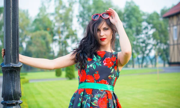 Kıvırcık saçlı, 50 'li yaşlarda, siyah elbiseli, kırmızı güllü muhteşem esmer kadın. Güzel kız sokaklarda yürüyor ve iyi bir ruh hali içinde harika hissediyor.