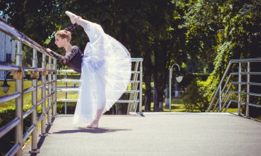 Yeşil manzarada dans eden beyaz etekli genç bir kadın. Güzel balerin klasik bale pozları veriyor. Kadın şefkati ve uyum içinde yaşam kavramı. Balerin Projesi