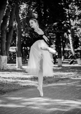 Yeşil manzarada dans eden beyaz etekli genç bir kadın. Güzel balerin klasik bale pozları veriyor. Kadın şefkati ve uyum içinde yaşam kavramı. Balerin Projesi