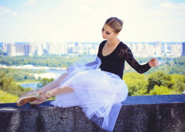 Yeşil manzarada dans eden beyaz etekli genç bir kadın. Güzel balerin klasik bale pozları veriyor. Kadın şefkati ve uyum içinde yaşam kavramı. Balerin Projesi