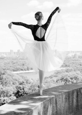 Yeşil manzarada dans eden beyaz etekli genç bir kadın. Güzel balerin klasik bale pozları veriyor. Kadın şefkati ve uyum içinde yaşam kavramı. Balerin Projesi