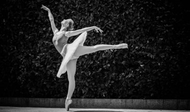 Yeşil manzarada dans eden beyaz etekli genç bir kadın. Güzel balerin klasik bale pozları veriyor. Kadın şefkati ve uyum içinde yaşam kavramı. Balerin Projesi