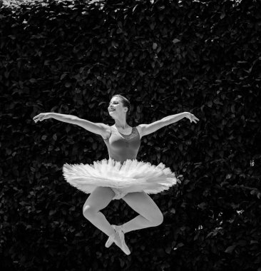 Yeşil manzarada dans eden beyaz etekli genç bir kadın. Güzel balerin klasik bale pozları veriyor. Kadın şefkati ve uyum içinde yaşam kavramı. Balerin Projesi