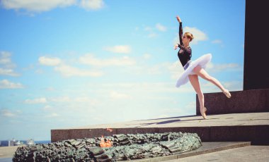 Yeşil manzarada dans eden beyaz etekli genç bir kadın. Güzel balerin klasik bale pozları veriyor. Kadın şefkati ve uyum içinde yaşam kavramı. Balerin Projesi