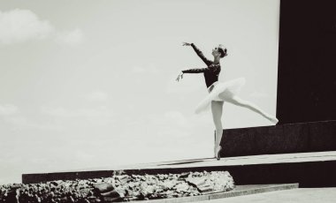 Yeşil manzarada dans eden beyaz etekli genç bir kadın. Güzel balerin klasik bale pozları veriyor. Kadın şefkati ve uyum içinde yaşam kavramı. Balerin Projesi