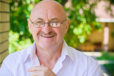 Beyaz gözlüklü, evinin yanında beyaz gömlekli yaşlı Amerikalı adam.