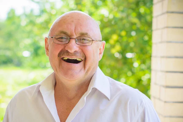 Older american man in white in glasses and white shirt near his house