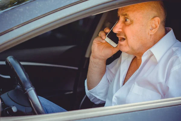 Mature European men talk to telephone. Modern technology for older people