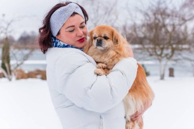Kış günü orta yaşlı, dolgun bir kadın, kırmızı Pekin köpeğiyle, artı evcil hayvanıyla cüsseli bir kadın.