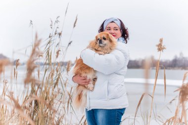 Kış günü orta yaşlı, dolgun bir kadın, kırmızı Pekin köpeğiyle, artı evcil hayvanıyla cüsseli bir kadın.