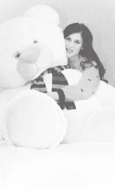 Genç ve güzel bir kadın, büyük oyuncak ayıya sarılıyor. Mutlu bir şekilde gülümsüyor. Komik kız ve büyük oyuncak ayı. Sevgililer günü hediyeleri