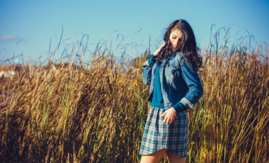 Sonbahar modasına uygun fikirler. Kot ceketli ve ekose elbiseli bir kadın. Modern moda.