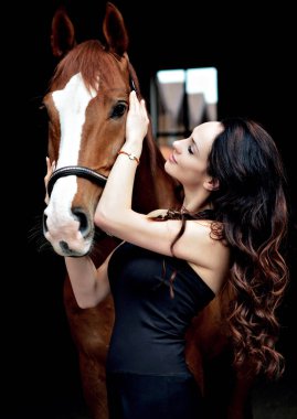 Ata binen zarif bir kadın atıyla konuşuyor. Şapkalı bir kadınla ata binmenin portresi. Binicisi ve eski ahırı olan bir binici atı..