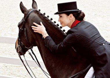 Ata binen zarif bir kadın atıyla konuşuyor. Şapkalı bir kadınla ata binmenin portresi. Binicisi ve eski ahırı olan bir binici atı..