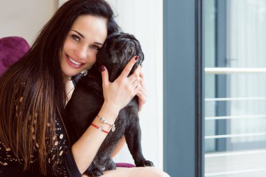 Evde sevimli köpekli hoş bir kadın var. Evcil hayvan evlat edinme, evcil hayvan hayatı. Pug taşıyan dişi, hayvanlar sağlıklı mutlu köpek yavrusu