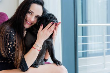 Evde sevimli köpekli hoş bir kadın var. Evcil hayvan evlat edinme, evcil hayvan hayatı. Pug taşıyan dişi, hayvanlar sağlıklı mutlu köpek yavrusu