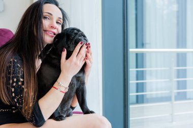 Evde sevimli köpekli hoş bir kadın var. Evcil hayvan evlat edinme, evcil hayvan hayatı. Pug taşıyan dişi, hayvanlar sağlıklı mutlu köpek yavrusu