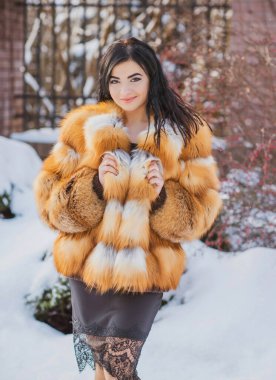 Moda konsepti. Tatillerde güzel bir Arap kadın, modern bir kadın kürk giyiyor. Havalı bayan açık hava portresi.