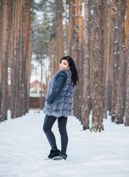 冬日里 穿着灰色皮大衣的女人在森林里散步 女士则是随和的时尚 — 图库照片