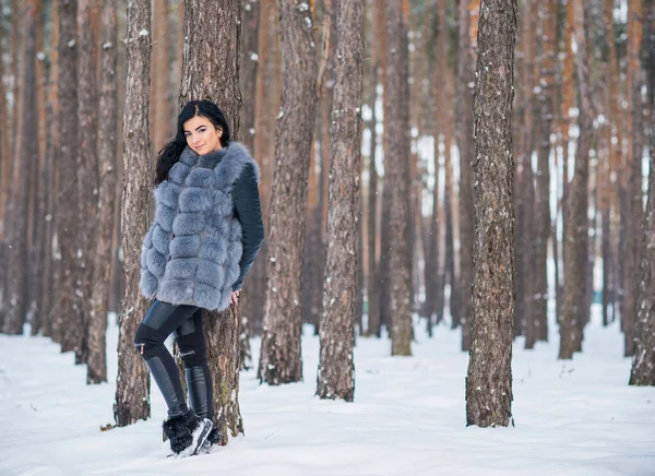 Gri kürklü kadın kış günü ormanda yürür, bayanlar gündelik moda.