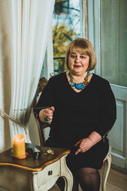Mistik ortamda olgun bir kadın, masadaki tarot kartı manzarası, esrarengiz kavram, falcılık ve tahminler. 