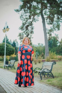 Klasik görünümlü orta yaşlı kadın parka bakıyor, tombul bayanlar için şık bir tarz. Olgun moda artı boyut kadın, orta yaşlı kadın yaşam tarzı kavramı.